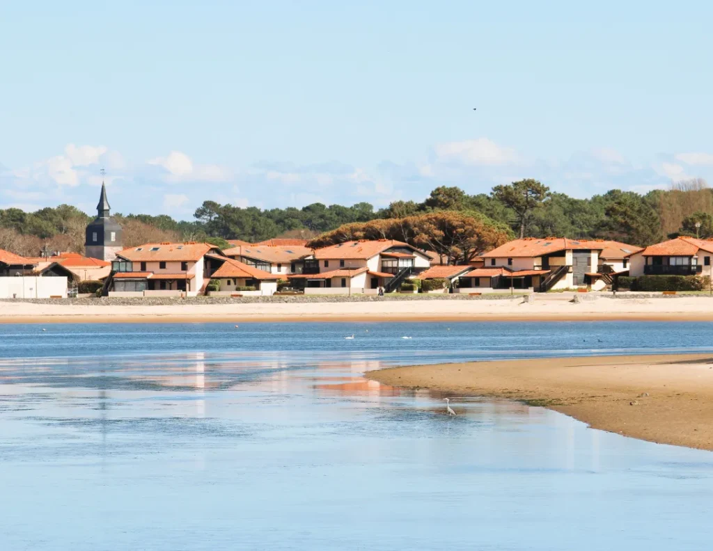 Une vue de résidences touristiques sur un lac dans un village bordé de forêt de pins à l'arrière plan