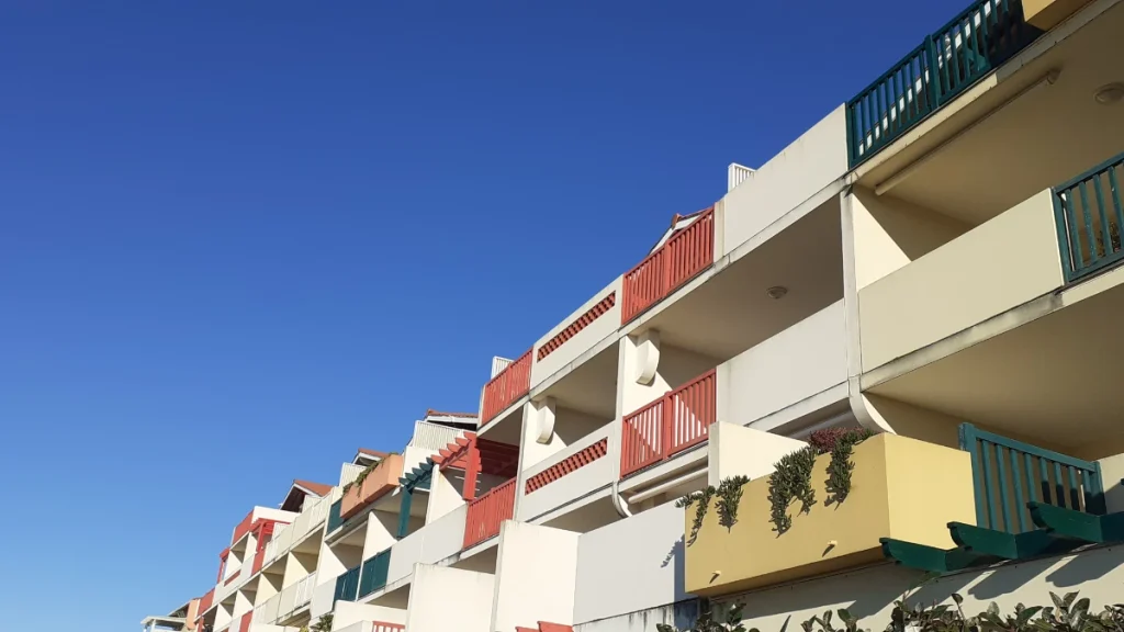 logement-louer Une résidence colorée de rouge, vert et jaune et ses balcons terrasses ensoleillés vue de profil