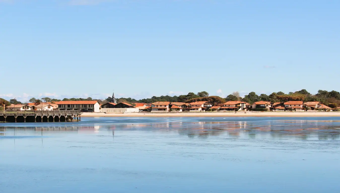 loger-location-village Vue d'ensemble d'un village aux petites maisons traditionnelles avec la forêt au fond et un lac au premier plan